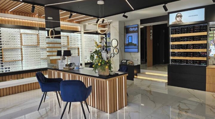 Wnętrze nowoczesnego salonu optycznego z ekspozycją okularów Ray-Ban, Prada i Chloé – elegancka lada recepcyjna, czarne sufity z oświetleniem LED, wystrój premium. Wnętrze nowoczesnego salonu optycznego z ekspozycją okularów Ray-Ban, Prada i Chloé – elegancka lada recepcyjna, czarne sufity z oświetleniem LED, wystrój premium.
