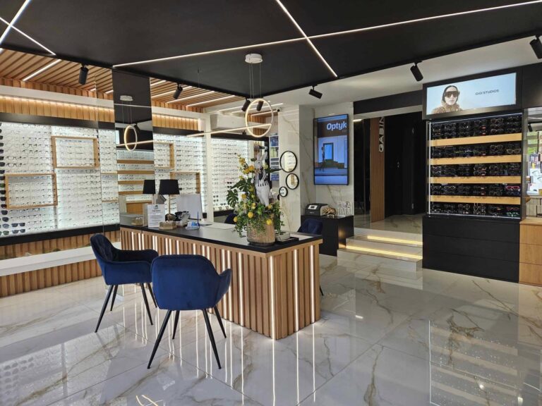 Wnętrze nowoczesnego salonu optycznego z ekspozycją okularów Ray-Ban, Prada i Chloé – elegancka lada recepcyjna, czarne sufity z oświetleniem LED, wystrój premium.